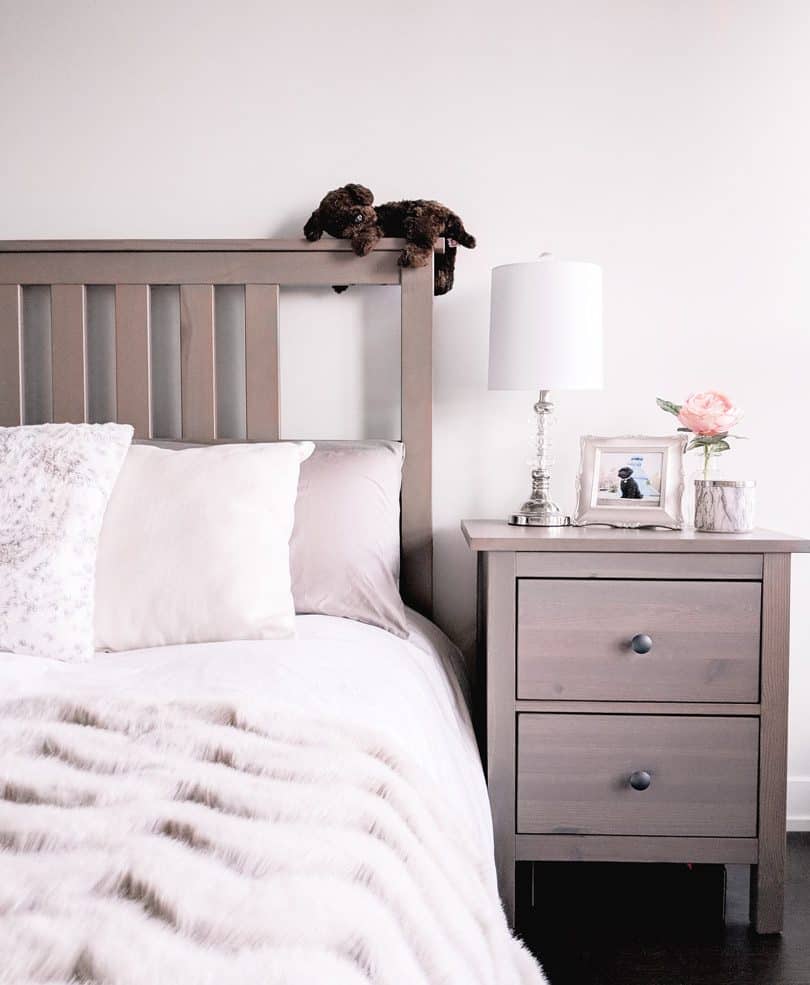 Simple bedroom design with wood night stand and fur throw in cozy neutral tones. 