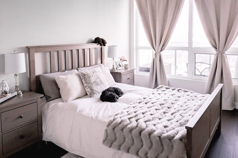 A cozy bedroom makeover with fresh linens, a fur throw, and textured pillows.