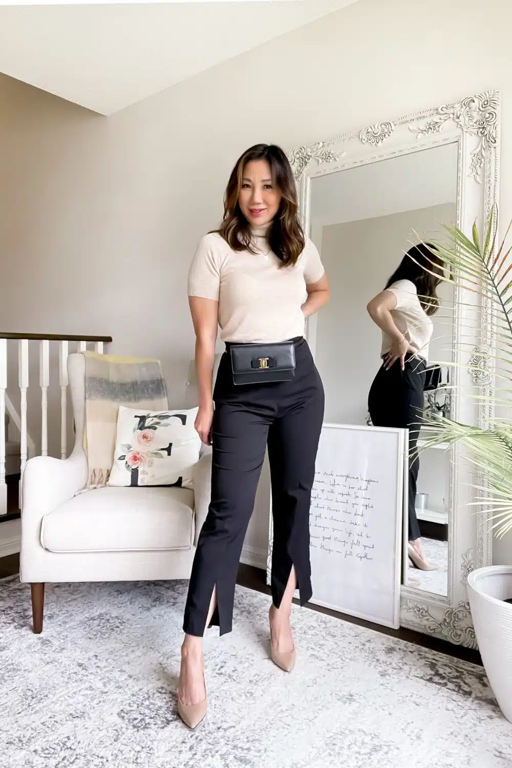 Chic office outfit with knit sweater and black pants with waist bag.