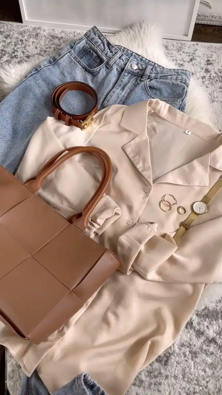 Outfiti flatlay with satin blouse, blue jeans, woven leather bag, Celine belt, gold jewelry and watch. 
