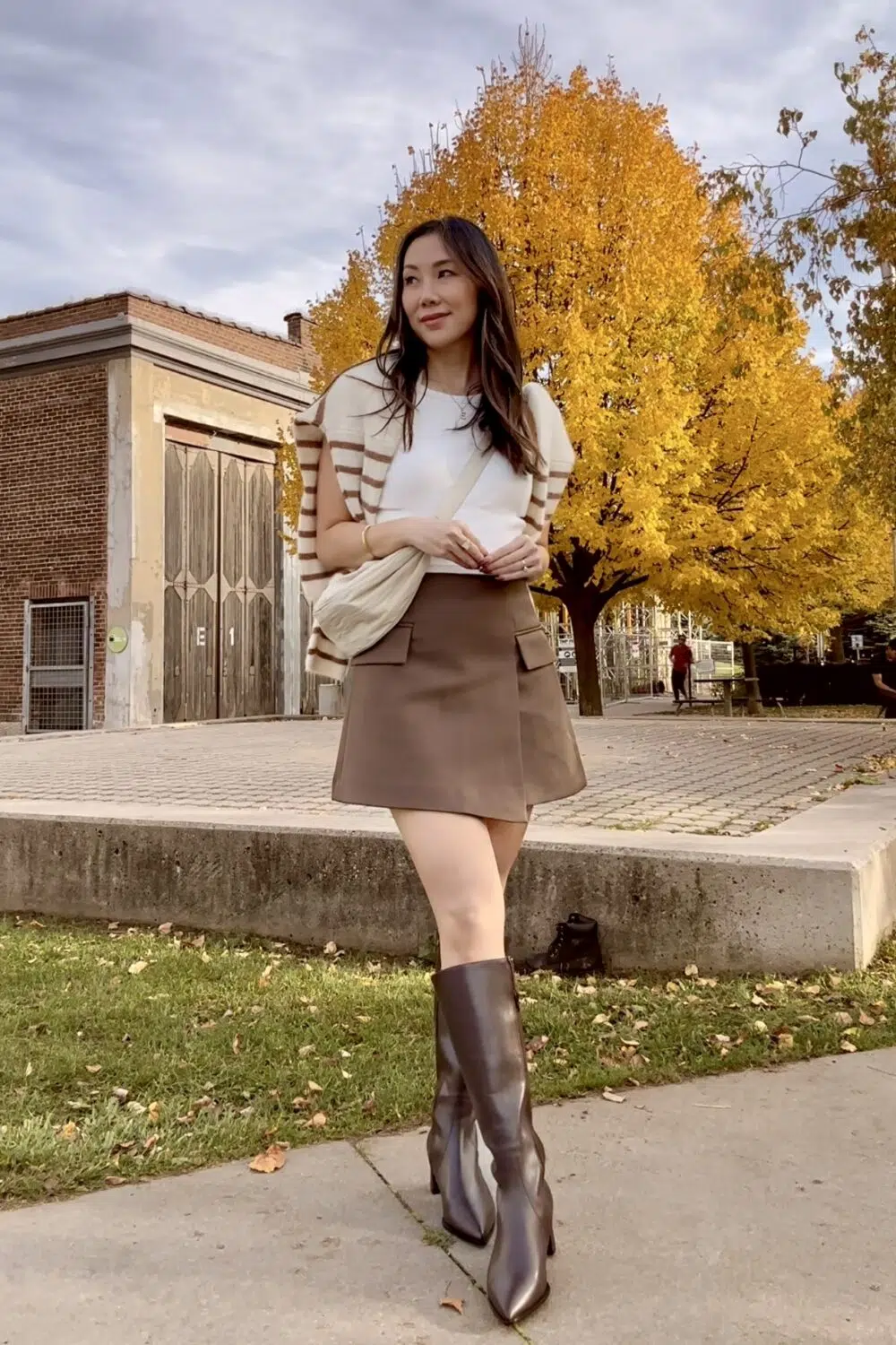 Dressed for a weekend getaway or just a city stroll—this fall outfit can do it all. 🍂 @ALLYShoes knee-high boots are built for comfort, paired with the Sezane cardigan and brown skort for an effortless look. Plus, the UNIQLO moon bag fits everything I need for the day. 🎒 #FallBoots #ClassyOutfit"