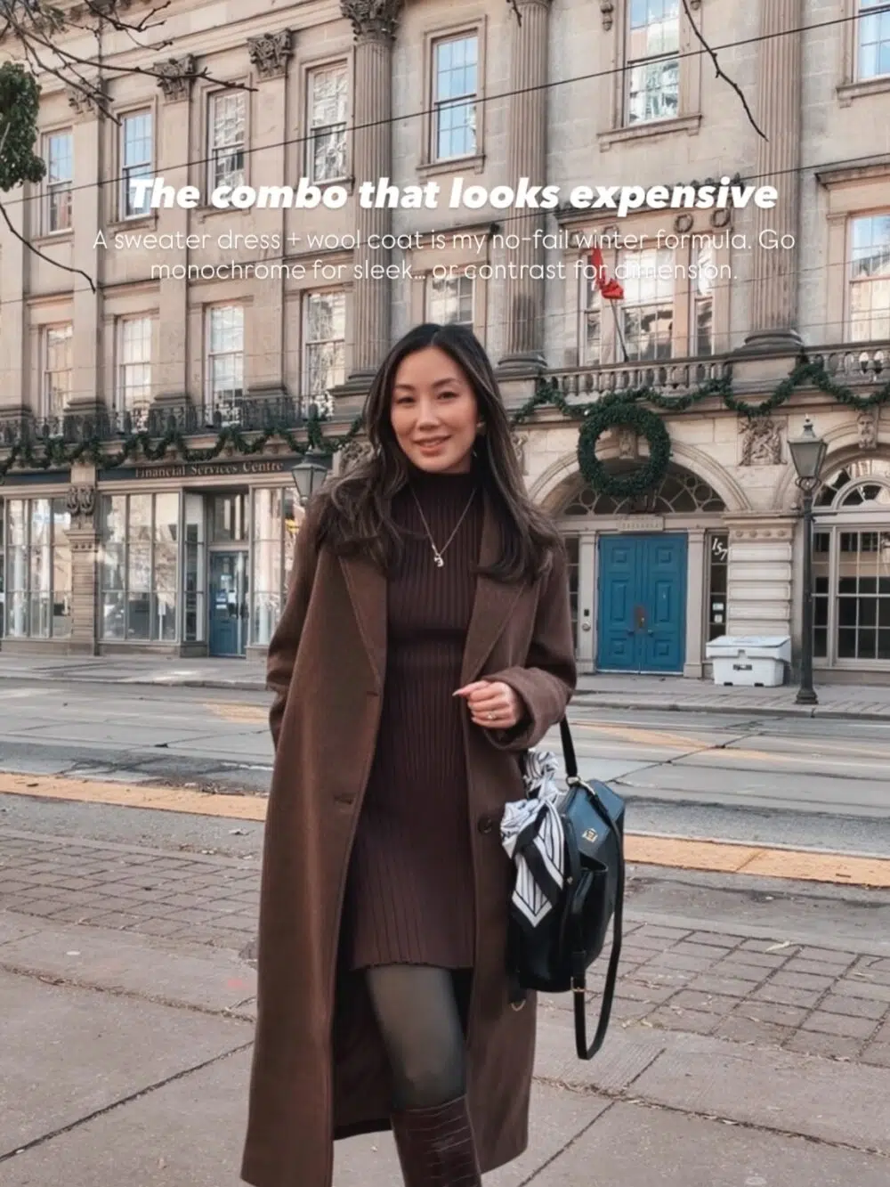 Best Luxury Handbag wearing a chic city winter outfit with a knit sweater dress layered under a long wool coat, styled with tall boots for an elevated and polished cold-weather look.